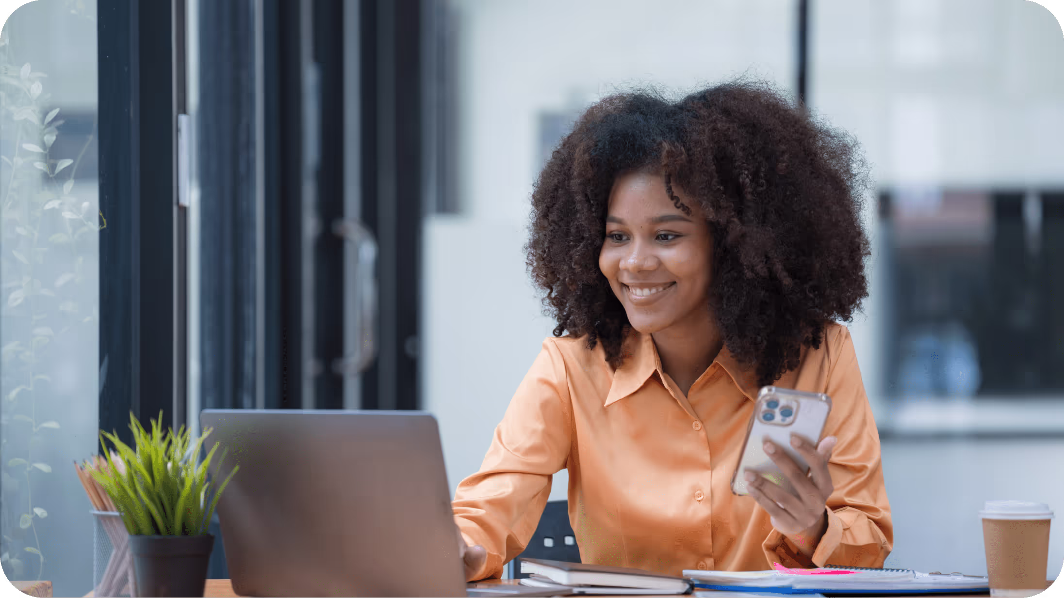 Lady in orange shirt smiling while holding mobile device
